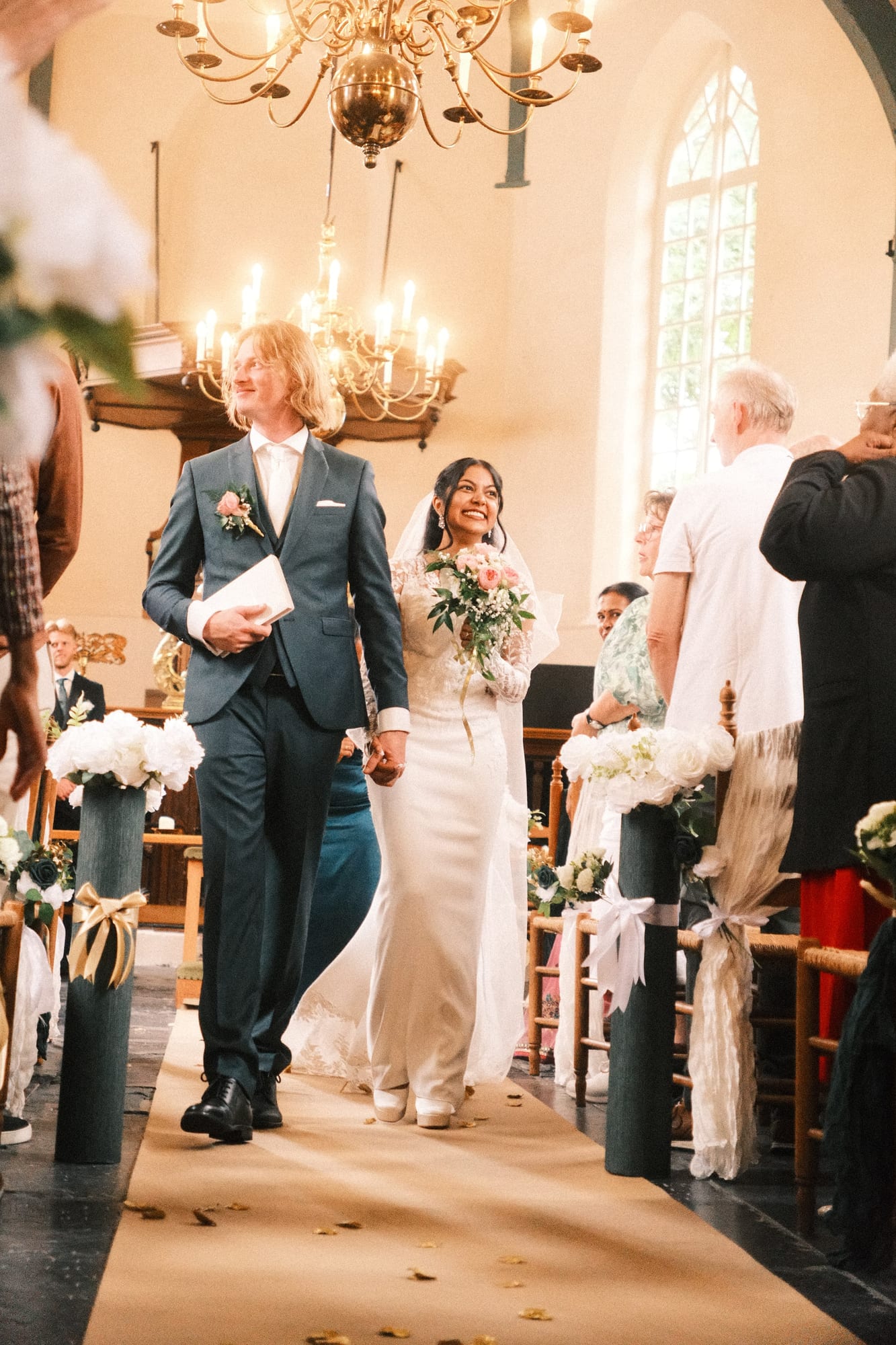 Het bruidspaar loopt na het jawoord door het gangpad van de kerk